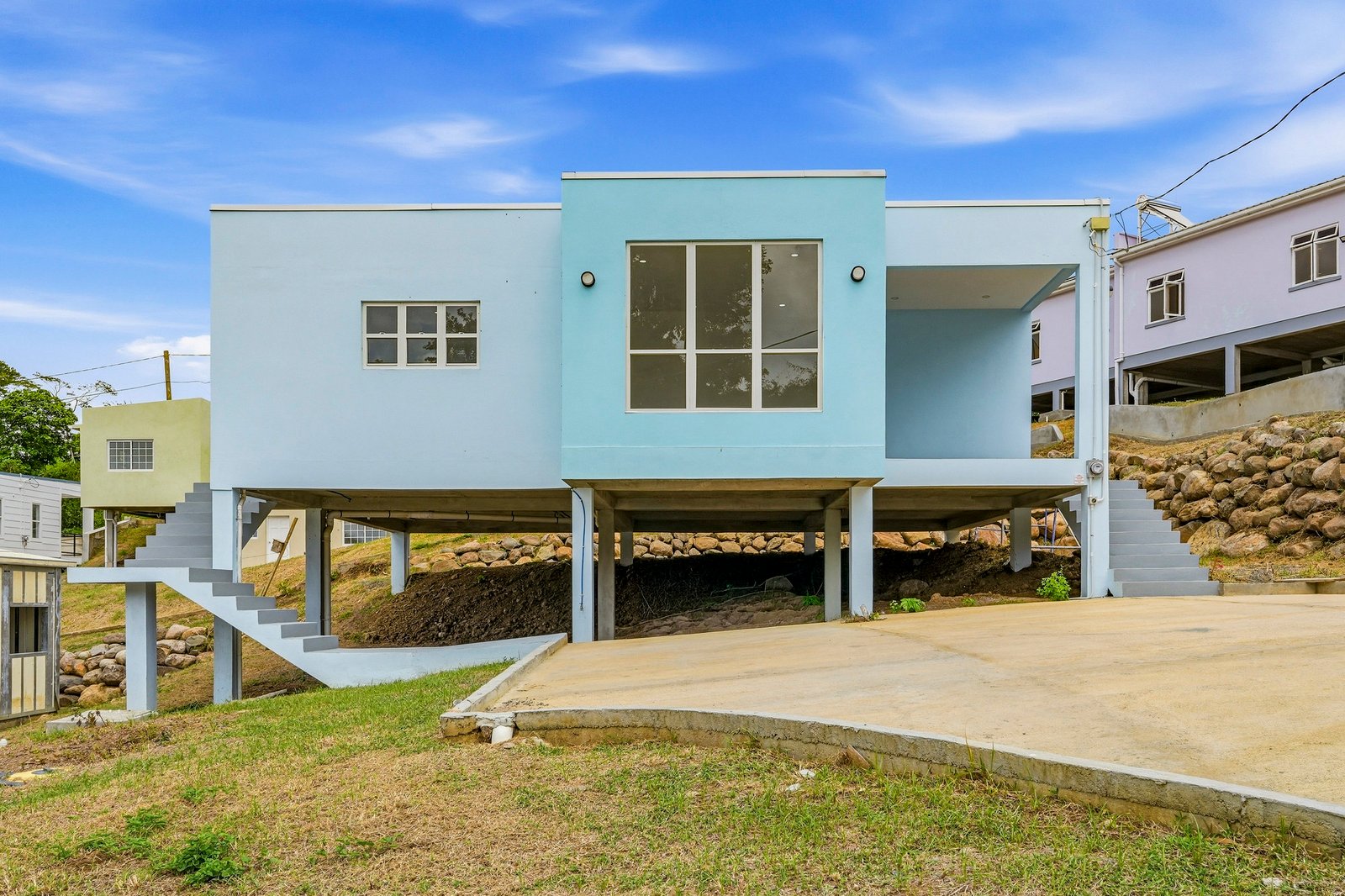 Allspice design, Lot 128: front exterior of the pale blue elevated house with entry steps.