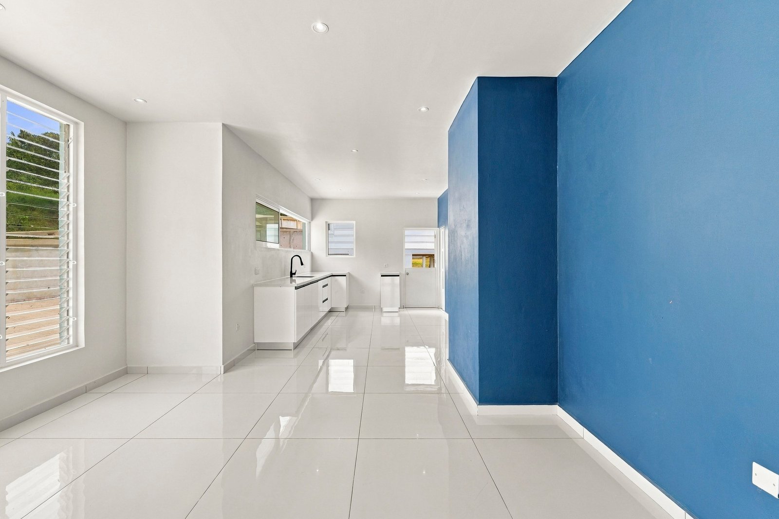 Bayleaf design, Lot 123: bright open-plan interior with a blue feature wall and kitchen beyond.