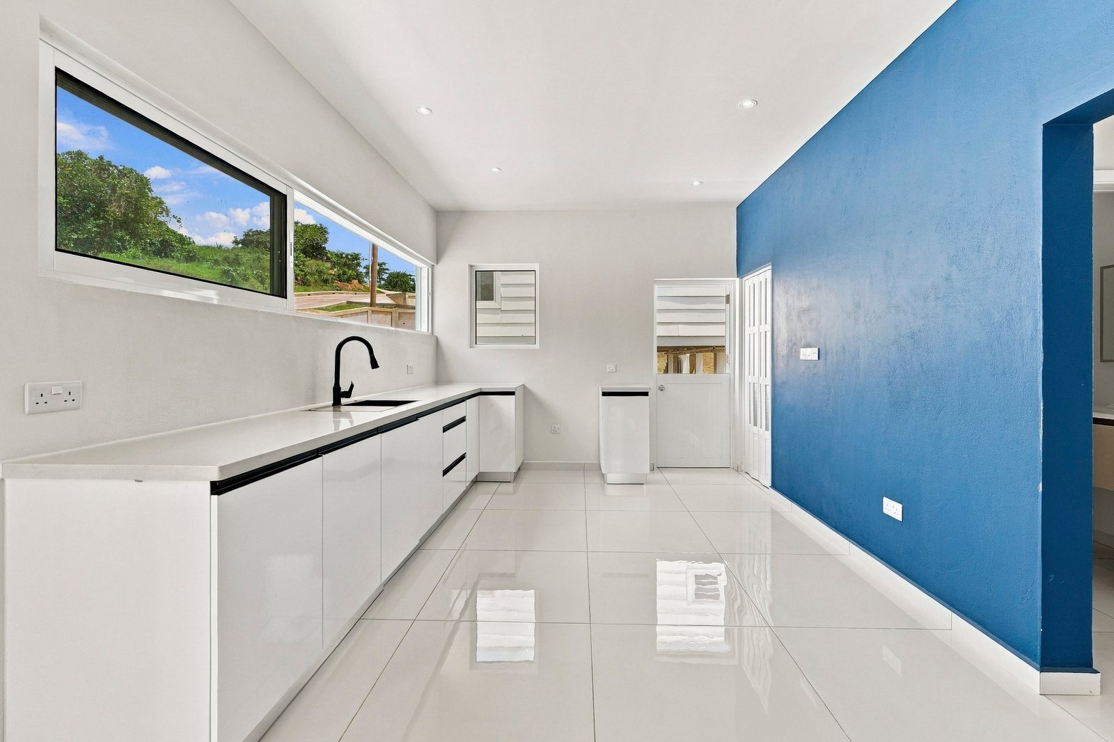 Bayleaf design, Lot 123: long white kitchen with black fittings and high horizontal windows.