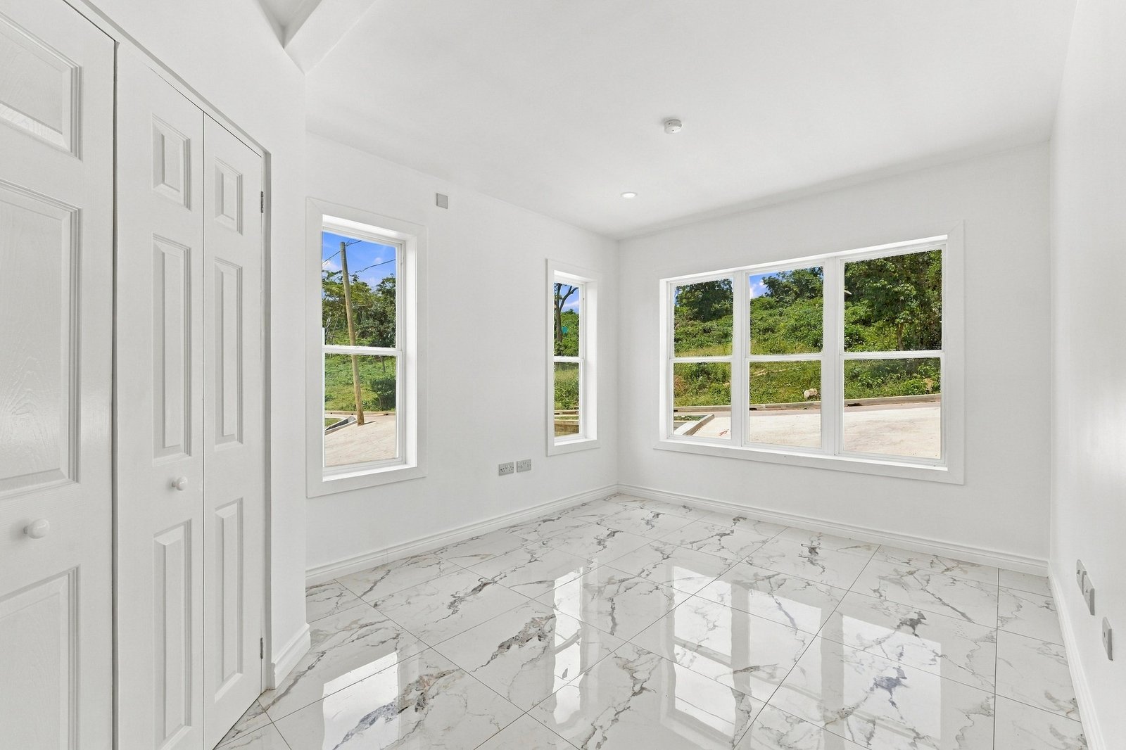 Cinnamon design interior with white cupboard doors, multiple windows and white-and-grey patterned floor tiles.
