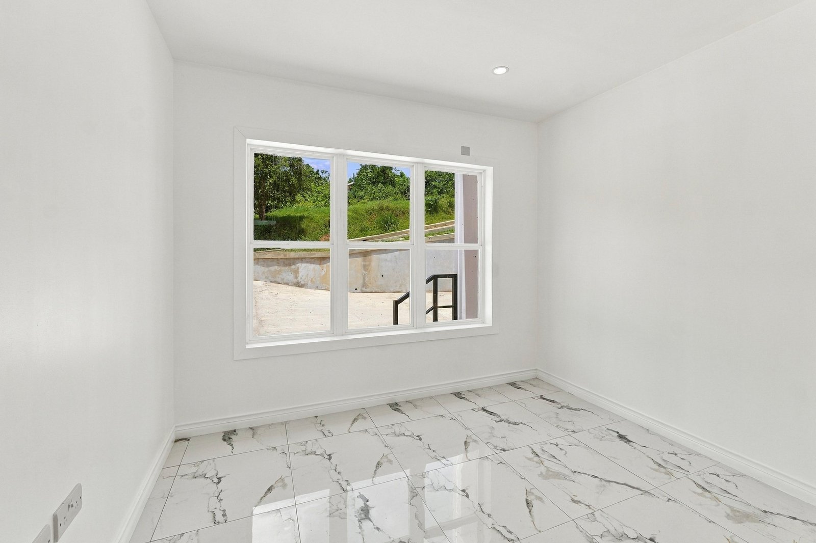Cinnamon design interior with white walls, a wide window and white-and-grey patterned floor tiles.