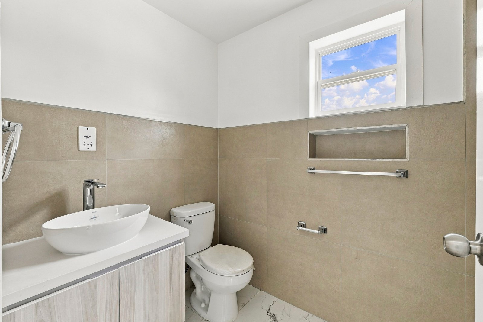 Cinnamon Lot 117 bathroom with a vessel basin, toilet, beige wall tiles, a recessed wall niche and a high window.