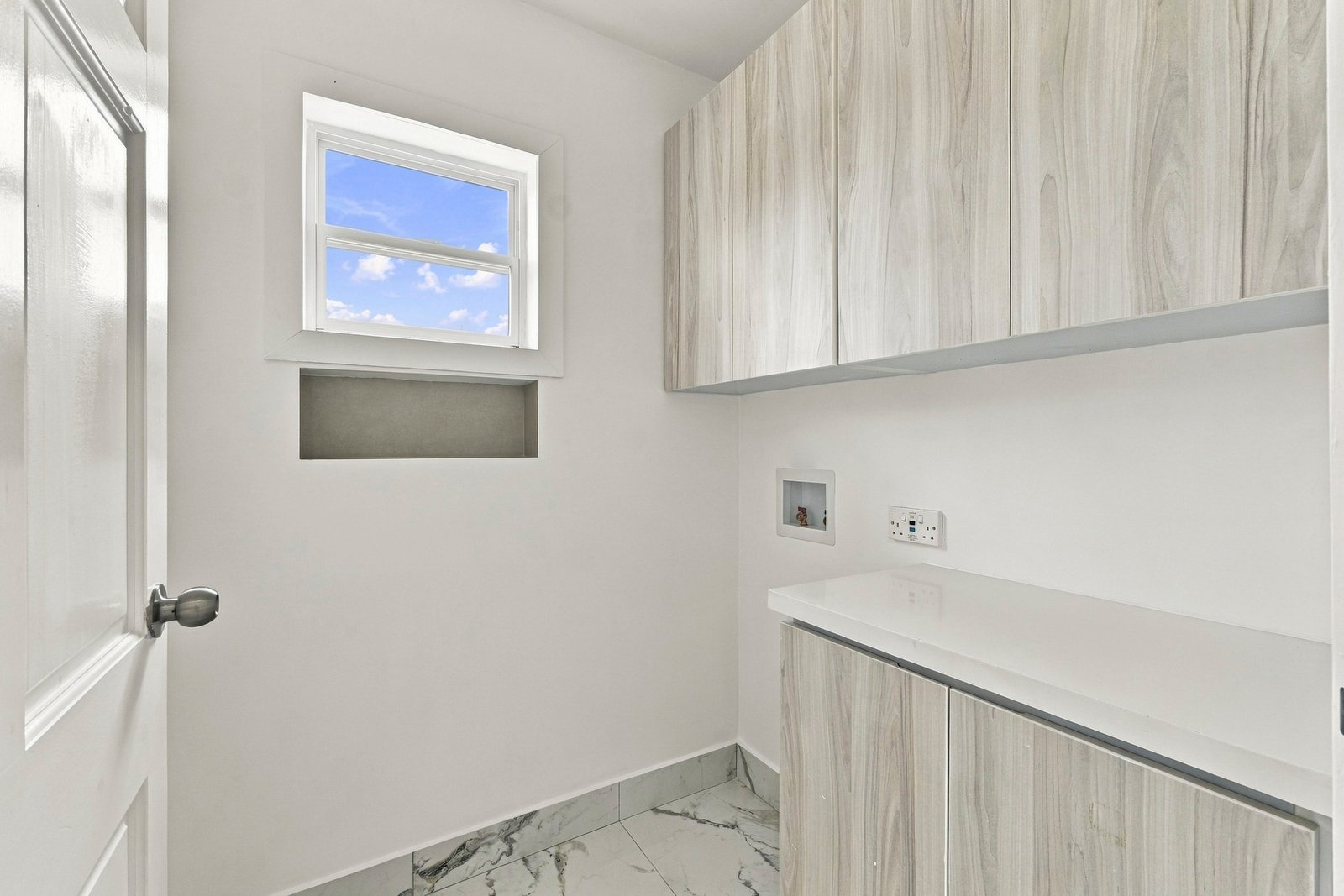 Small room at Cinnamon Lot 117 with pale wood-grain cabinets, a countertop, a wall connection and a high window.