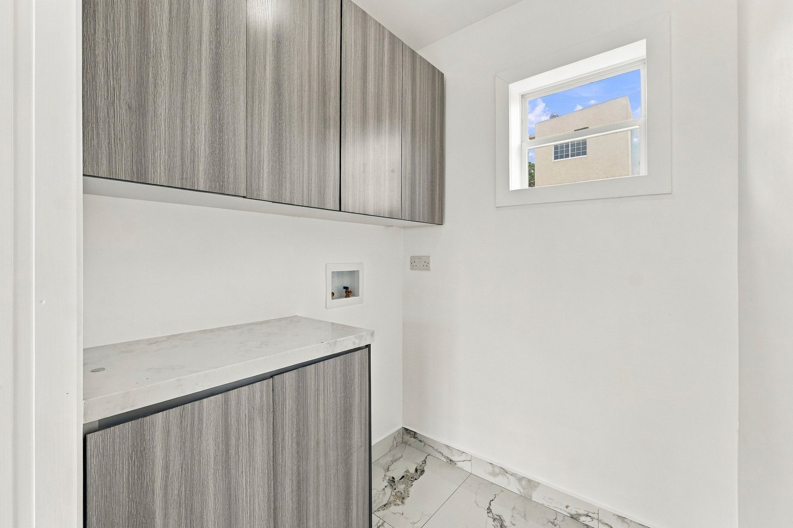 Small room at Cinnamon Lot 120 with grey wood-grain cabinets, a pale countertop, a wall connection and a high window.