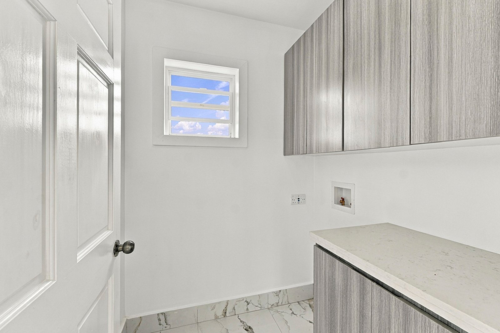 Small room at Cinnamon Lot 125 with grey wood-grain cabinets, a countertop, a wall connection and a high window.