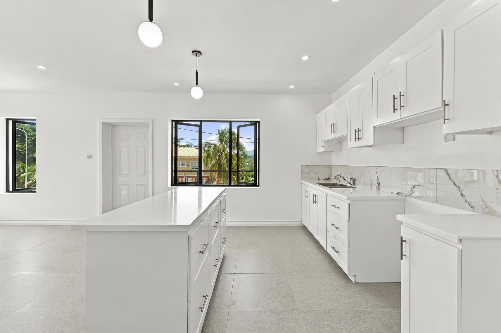 Kitchen in the Clove home on Lot 116, with a white island, fitted cabinets, sink and pendant lights.