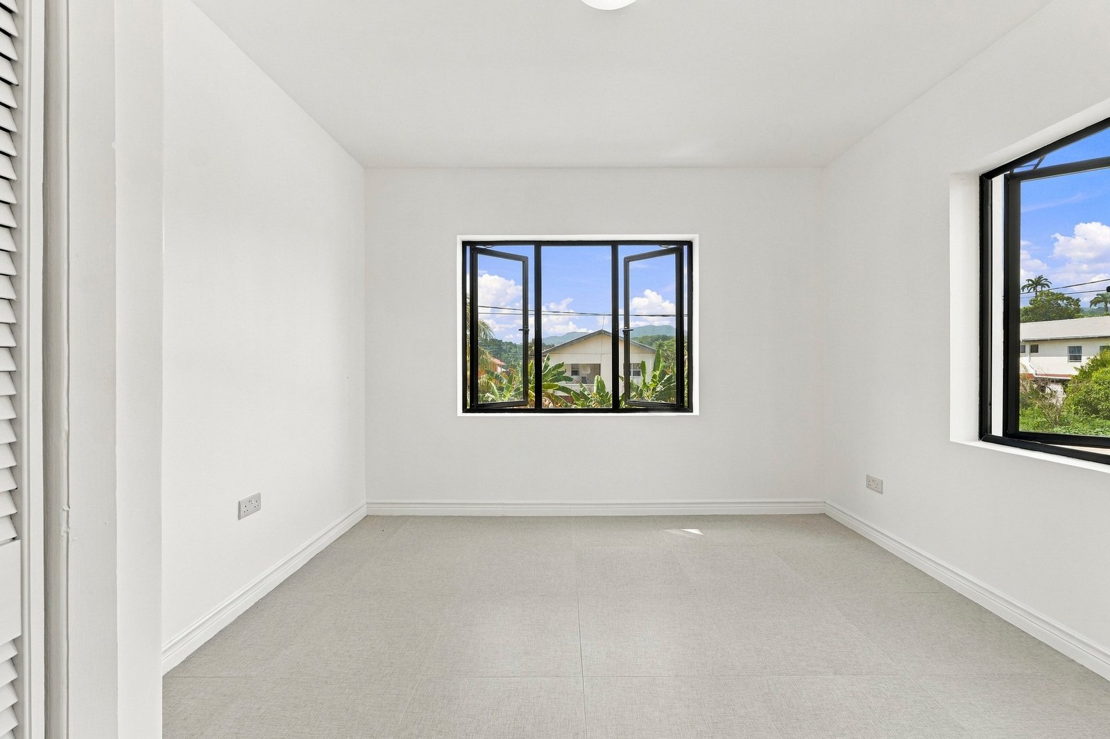 Unfurnished room in the Clove home on Lot 116, with grey floor tiles and windows on adjoining walls.