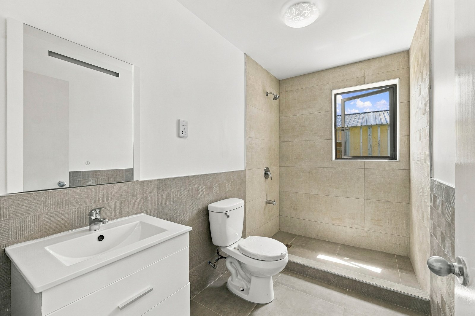 Bathroom in the Clove home on Lot 116, with a white vanity, toilet and tiled shower beneath a window.
