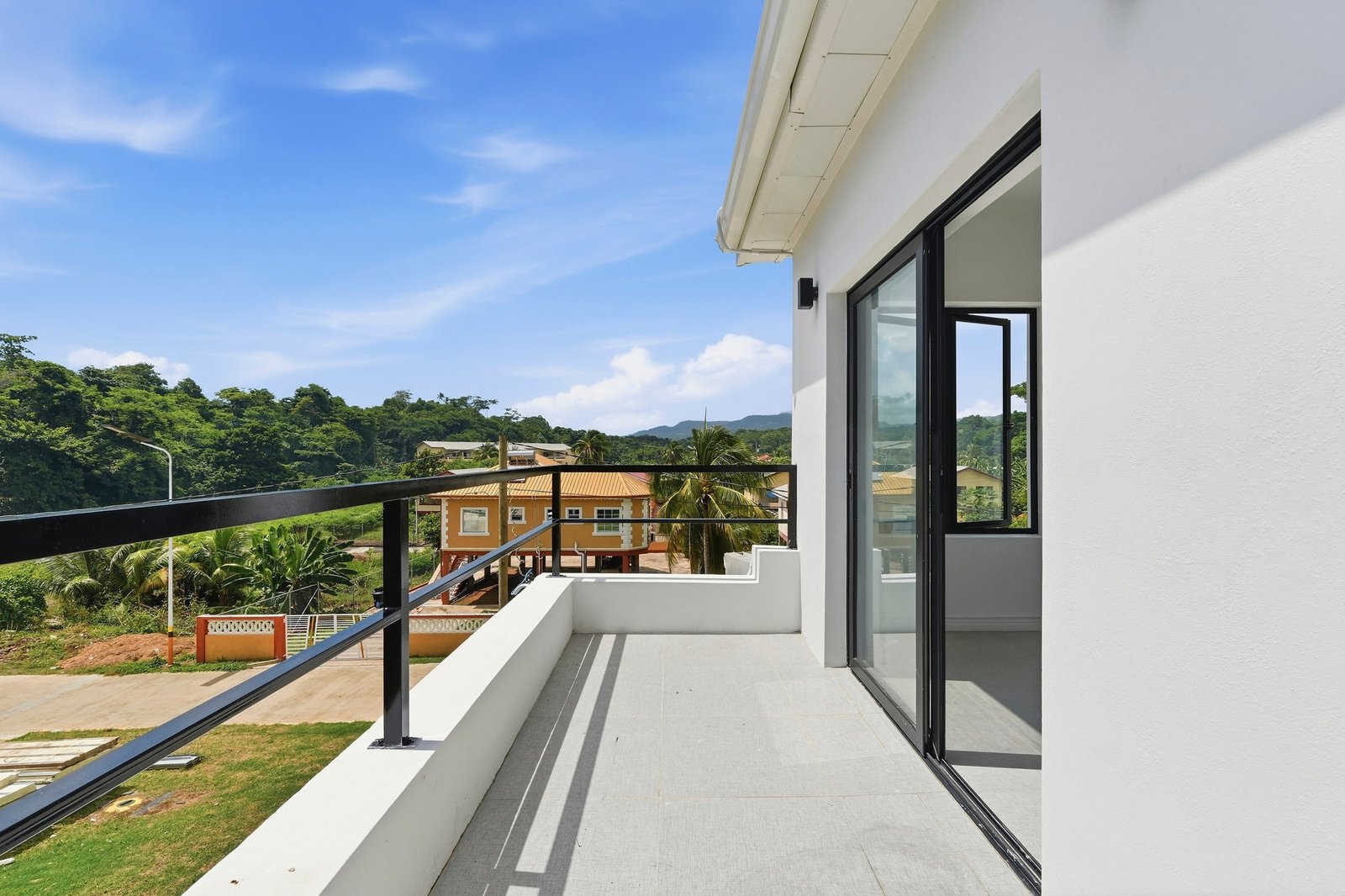 Upper balcony of the Clove home on Lot 116, with black railings, a sliding glass door and neighbourhood views.