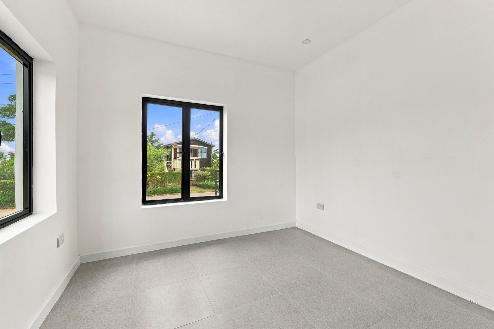 Unfurnished room in the Clove home on Lot 130, with a smaller front window, side window and grey tiled floor.