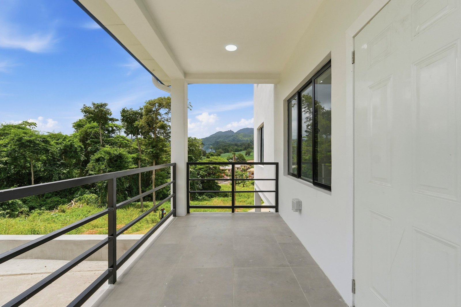 Covered entrance porch of the Clove home on Lot 130, with black railings and views toward the green hills.